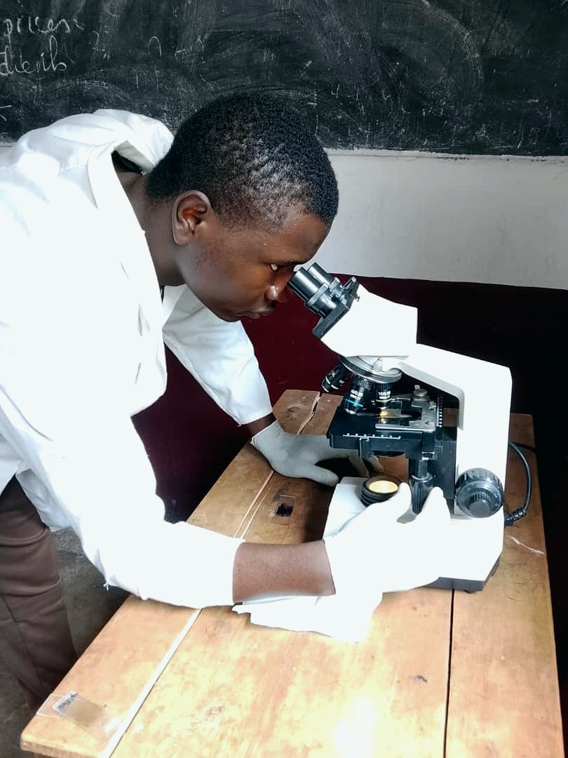 The student examining faecal-floatation slides under the microscope — a real photo from the study.